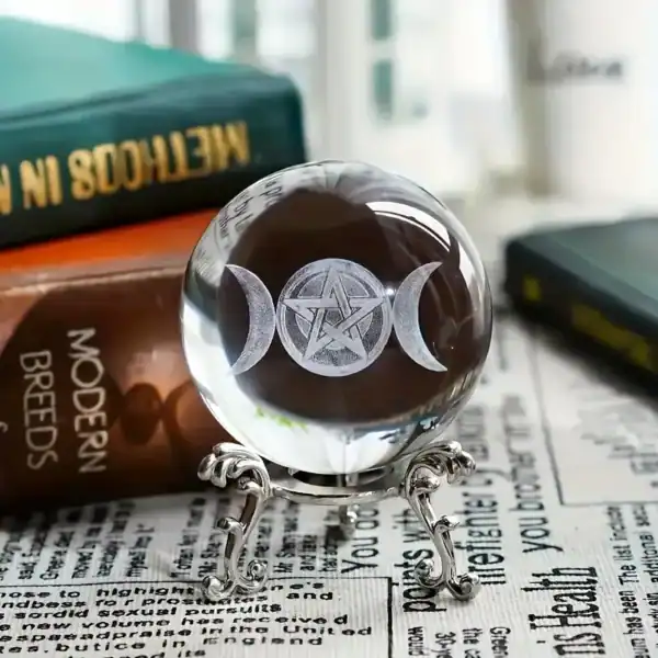 Crystal ball engraved with Triple Moon and pentacle symbol on an ornate silver stand, with candlelight and mystical ambiance in the background.