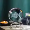 Crystal ball engraved with Triple Moon and pentacle symbol on an ornate silver stand, with candlelight and mystical ambiance in the background.