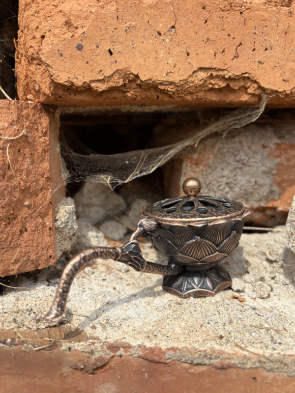 Antique-style bronze incense holder with flower pattern,against a rustic brick background