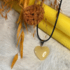Yellow heart pendant surrounded by dried oats, mushroom, and autumn tones