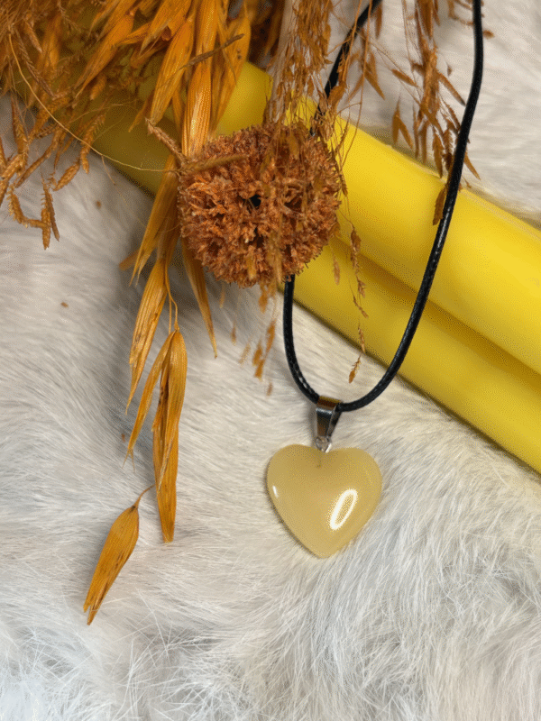 Yellow heart pendant surrounded by dried oats, mushroom, and autumn tones
