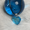 Blue heart pendant resting against a deep blue glass sphere on white fur