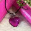 Purple heart pendant with black cord, styled with pink candles and moss