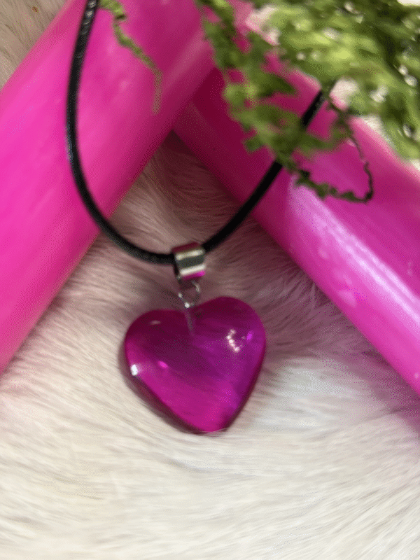 Purple heart pendant with black cord, styled with pink candles and moss