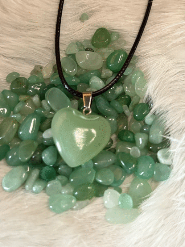 Opaque green heart pendant on a bed of green tumbled stones