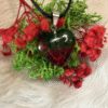 Watermelon-colored heart pendant (green and red) on black cord, styled with preserved moss and red flowers