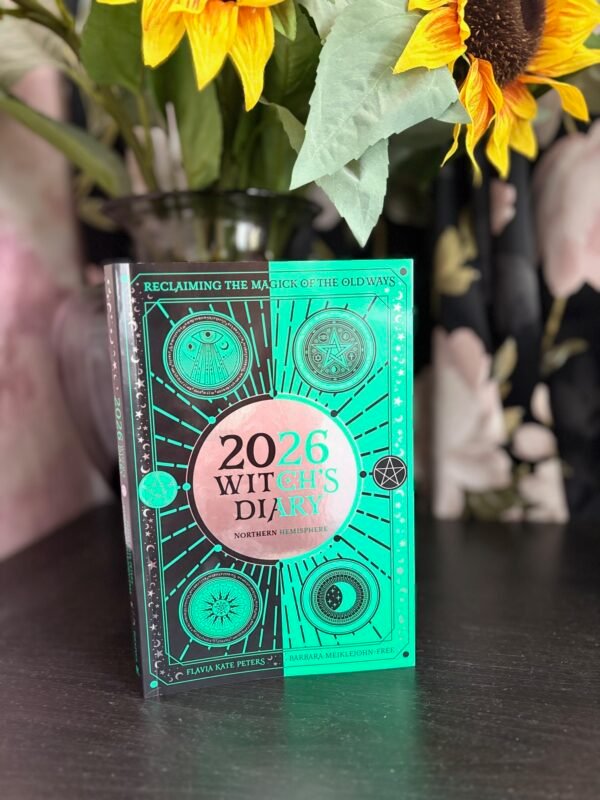 2026 Witch’s Diary standing in front of sunflowers and a dark floral background, mystical and vibrant.