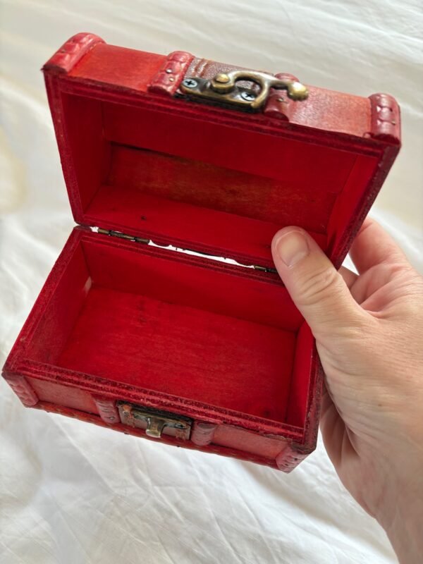 A small red wooden spell chest with vintage brass clasp, perfect for storing magical tools or using as a travel altar. Pictured open and closed, styled with runes, candle and witchy decor.