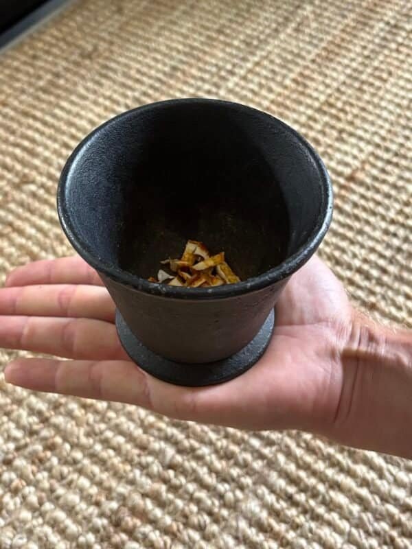 Hand holding an antique cast iron cauldron, showcasing its size and textured patina.Hand holding an antique cast iron cauldron, showcasing its size and textured patina.