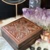 Antique wooden altar box with embossed Viking-inspired symbols, styled with runes, crystals, candlelight, and herbs.