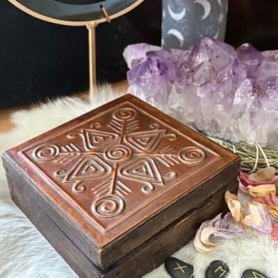 Antique wooden altar box with embossed Viking-inspired symbols, styled with runes, crystals, candlelight, and herbs.