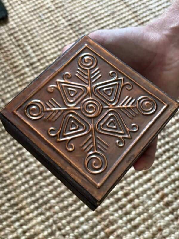 Hand holding an antique wooden altar box with embossed Nordic-style symbols, showing its compact size.
