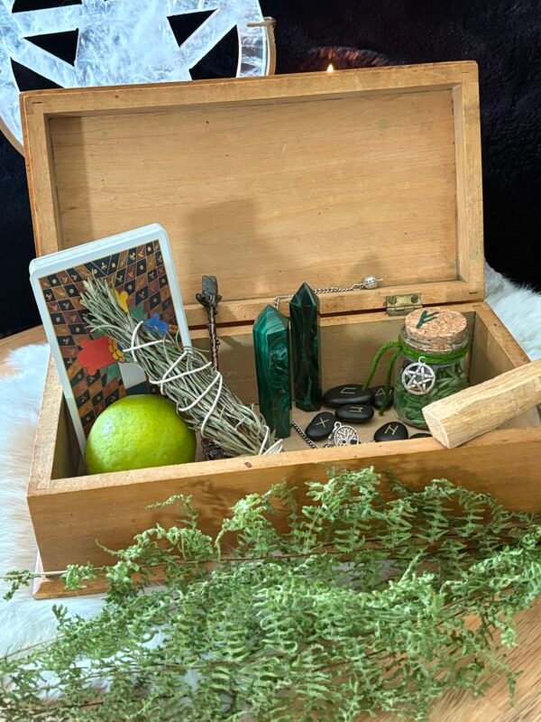 Open wooden box filled with tarot cards, crystals, herbs, and runes.