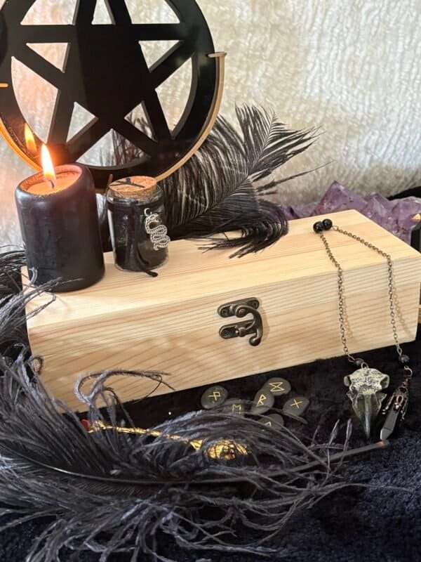 Unfinished handcrafted wooden box with metal clasp, displayed with black candle, runes, and feathers – perfect for witchcraft tools, tarot cards, or personalized altar storage.