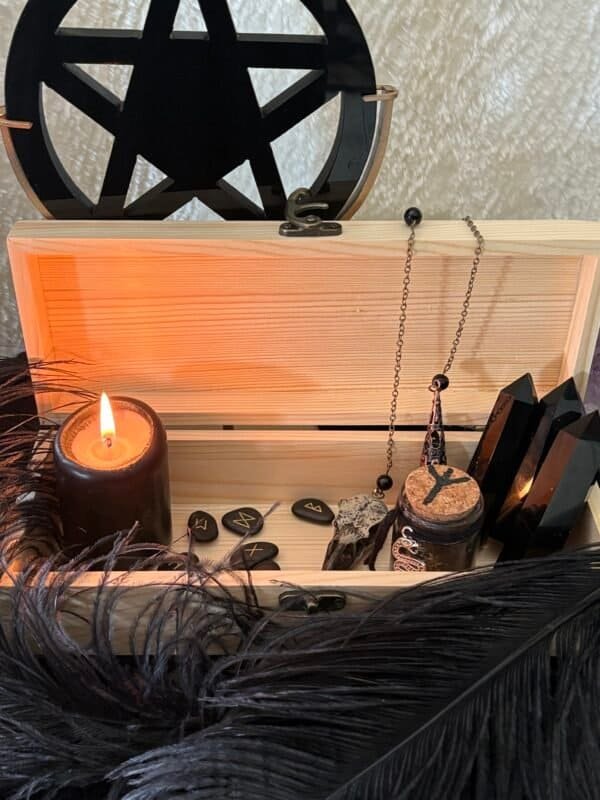 Unfinished handcrafted wooden box with metal clasp, displayed with black candle, runes, and feathers – perfect for witchcraft tools, tarot cards, or personalized altar storage.