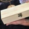 Hand holding a Unfinished handcrafted wooden box with metal clasp