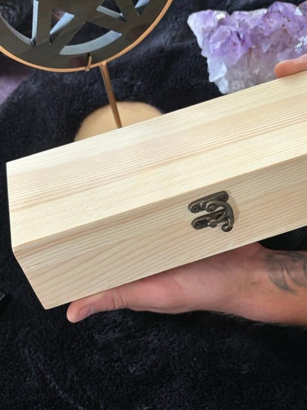 Hand holding a Unfinished handcrafted wooden box with metal clasp