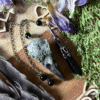Obsidian crystal pendulum with raven skull detail, photographed against natural background, gothic witch style