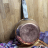 Backside of vintage copper cauldron with aged patina – surrounded by dried flower petals