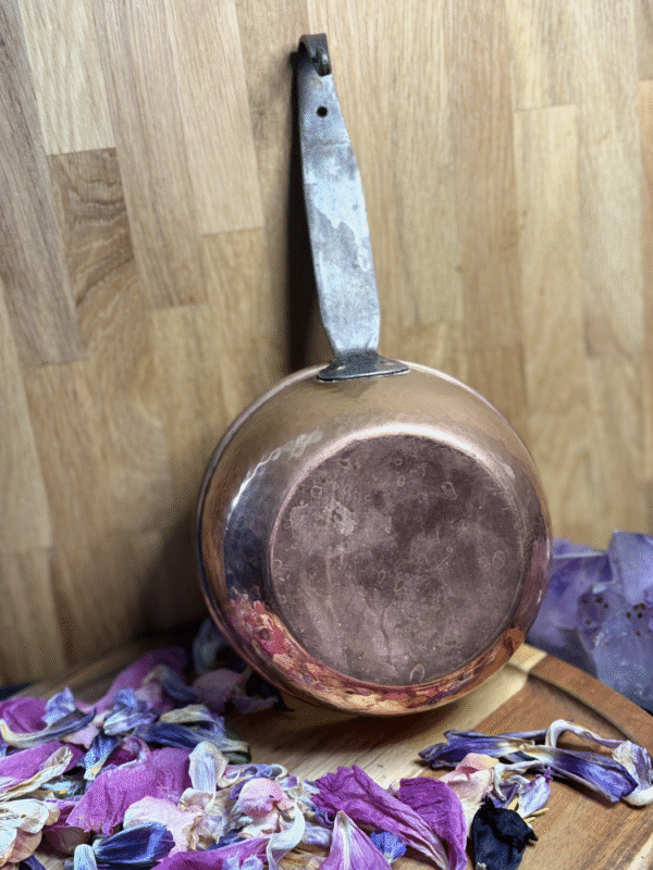 Backside of vintage copper cauldron with aged patina – surrounded by dried flower petals