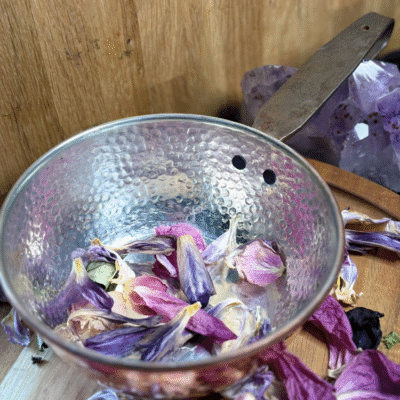 Vintage hammered copper cauldron with iron handle and silver interior – displayed with dried flower petals