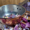 Close-up of hammered copper cauldron rim and textured surface – resting in dried purple petals