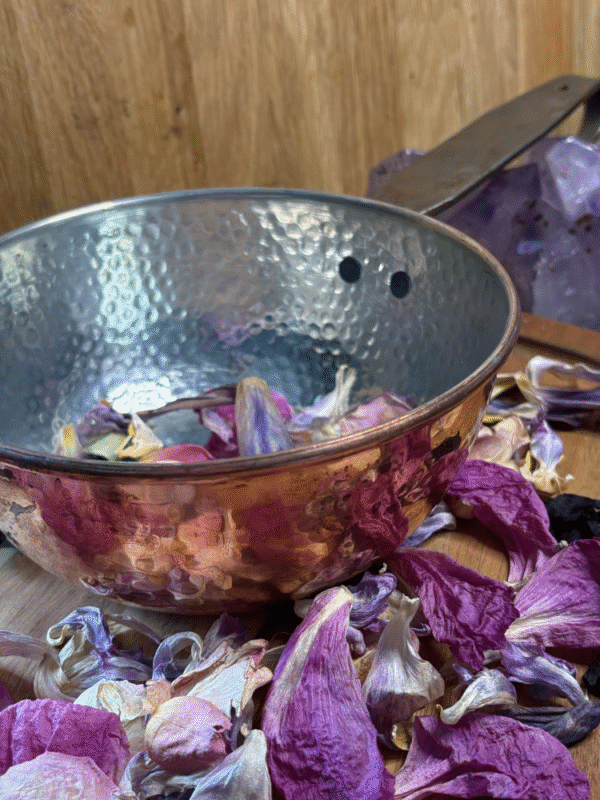 Close-up of hammered copper cauldron rim and textured surface – resting in dried purple petals