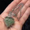 Green aventurine resin pendulum with Tree of Life charm and copper spiral, displayed in an open palm.