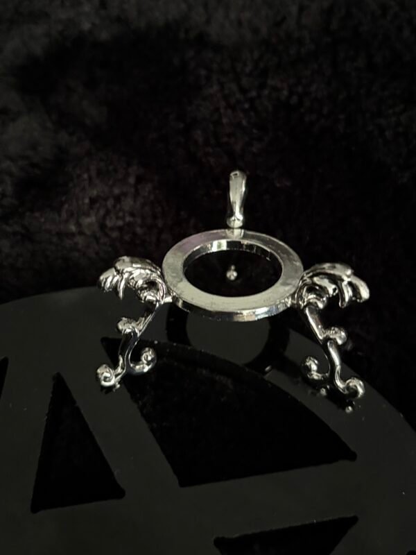 Silver crystal ball stand with ornate detailing, displayed on a black pentacle background.