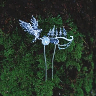 Silver hair comb with owl and forest motif resting on green moss, handcrafted nature-inspired jewelry.