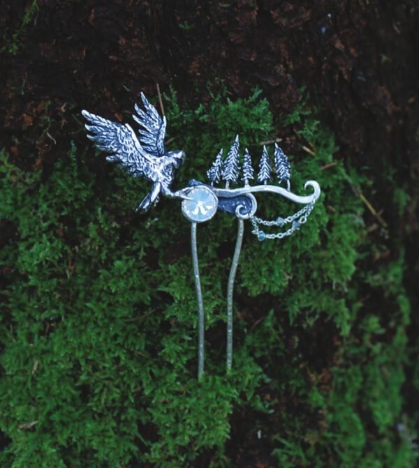 Silver hair comb with owl and forest motif resting on green moss, handcrafted nature-inspired jewelry.
