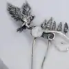 Close-up of a handcrafted silver hair comb with an owl and pine trees, featuring a glass opal stone, on a white background.