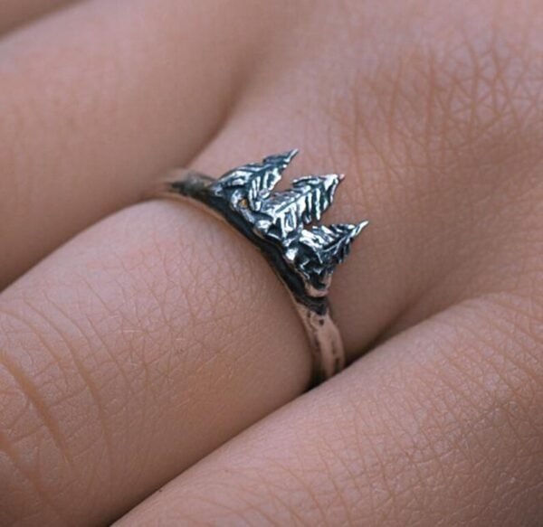 Diser silver ring worn on a hand, highlighting the intricate pine tree design.