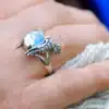 Close-up of owl silver ring with opal glass stone on hand, natural light glow.