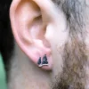 Silver pine tree stud earrings worn on a man's ear, symbolizing strength and nature.