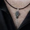 Man wearing the silver owl pendant on a black leather cord, styled with an open black shirt.