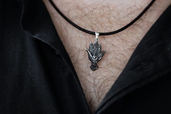 Man wearing the silver owl pendant on a black leather cord, styled with an open black shirt.
