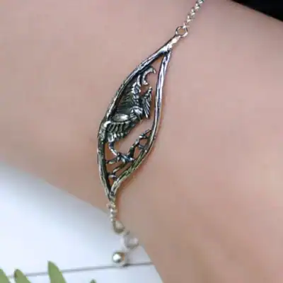 Close-up of the "Nattuggla" silver bracelet with an owl, moon, and forest design, displayed on a wrist.
