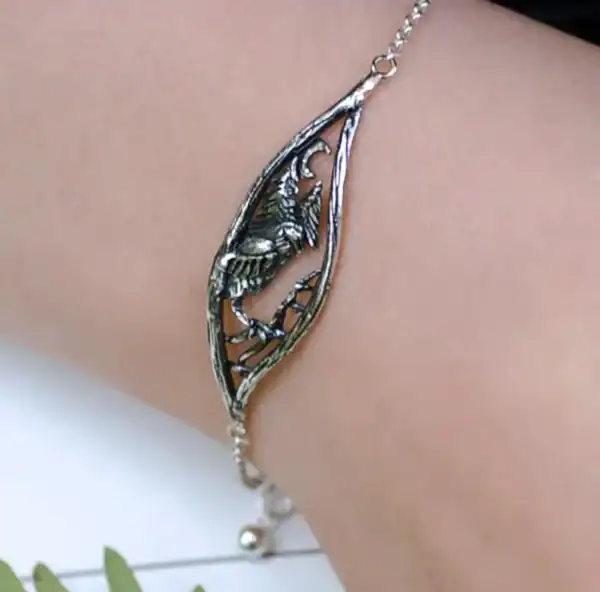 Close-up of the "Nattuggla" silver bracelet with an owl, moon, and forest design, displayed on a wrist.