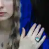 Woman in blue cloak wearing owl silver ring with glowing opal stone.