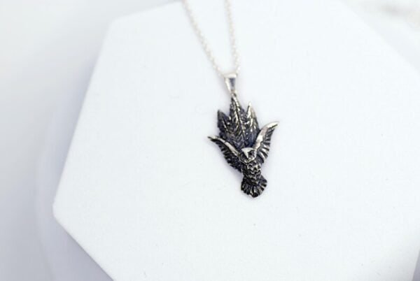 Detailed view of the owl pendant with engraved forest trees, symbolizing nature and protection.
