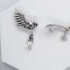 Pair of silver owl earrings with opal glass drops shown flat on white background.